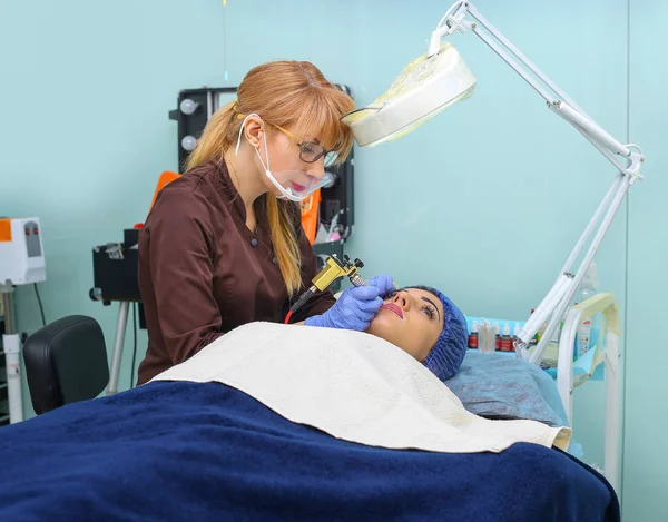 Cosmetologist making permanent makeup on woman's face — Stock Photo, Image