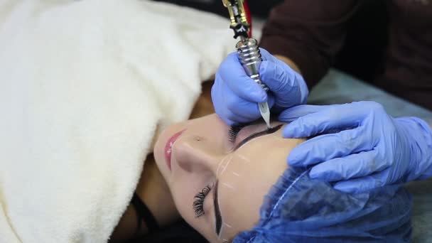 Cosmetologist making permanent makeup on woman's face — Stock Video