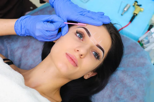 Молодая красивая женщина делает постоянный макияж в косметологическом салоне . — стоковое фото