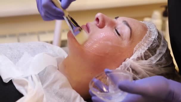 Application de gel cosmétique sur le patient du visage . — Video