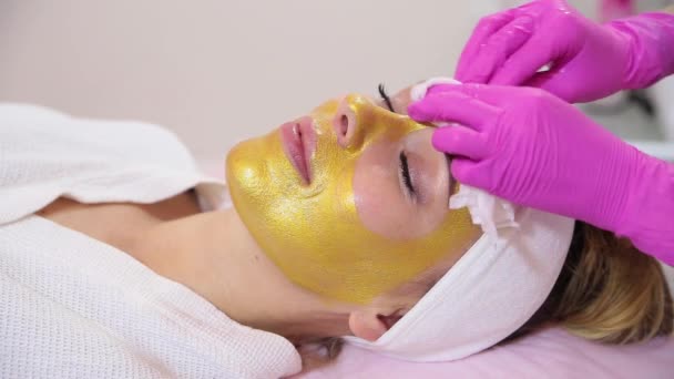 Saloon de beauté. Rincer un masque doré du visage du modèle . — Video