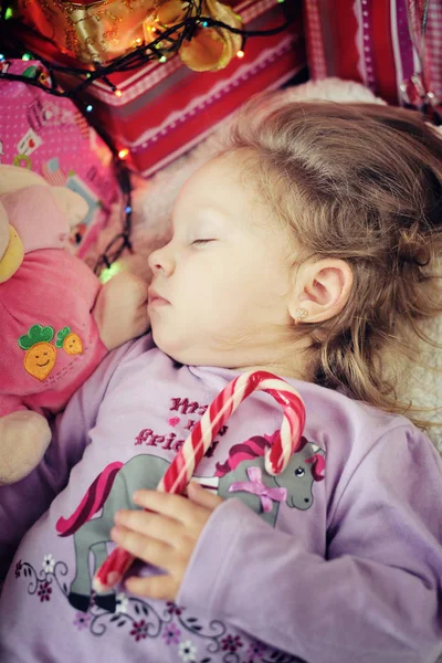Cute little girl sleeping with a toy and  candy cane — Stock Photo, Image