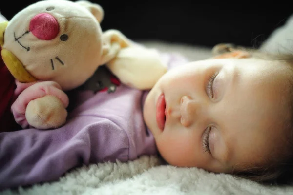 Милая маленькая девочка спит с игрушкой и конфеткой — стоковое фото