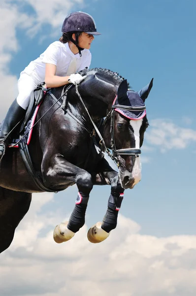 Jovem no cavalo preto no salto show — Fotografia de Stock