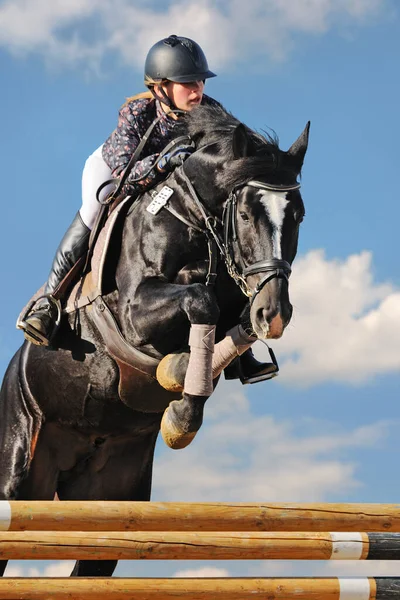 Νεαρή κοπέλα στο μαύρο άλογο στο άλμα δείχνουν — Φωτογραφία Αρχείου