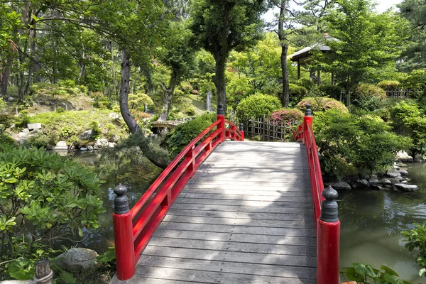 Puente rojo clásico en un jardín japonés — Foto de Stock