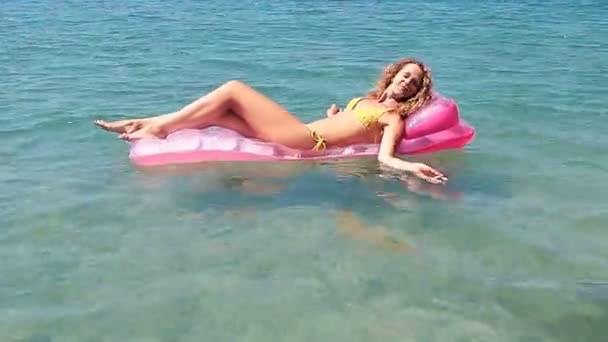 Beautiful young girl floating on a mattress in the sea — Stock Video