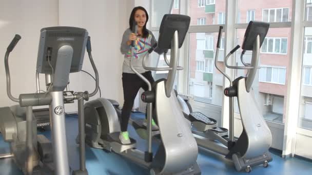 Beautiful female during exercise on elliptical trainer. — Videoclip de stoc