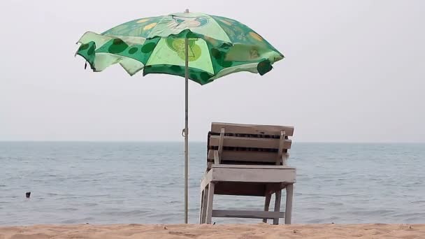 Stol med paraply nära stranden — Stockvideo