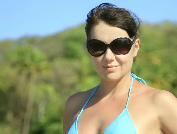 Портрет женщины в солнечных очках, позирующей на тропическом пляже — стоковое фото