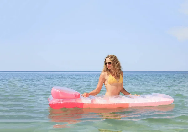 Hermosa joven flotando en un colchón en el mar — Foto de Stock