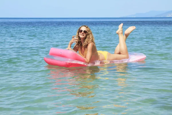 Bella ragazza galleggiante su un materasso nel mare — Foto Stock