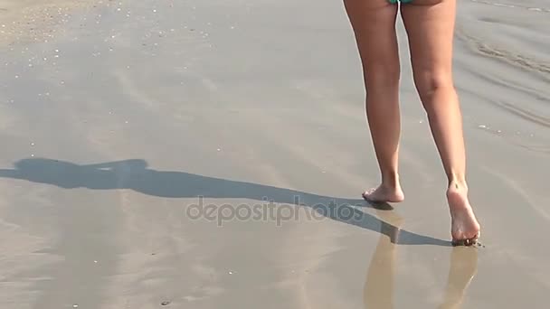 Девушка ходит по песчаному пляжу оставляя следы — стоковое видео