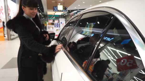 Femme inspectant sa nouvelle voiture dans le showroom — Video