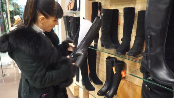 Giovane ragazza sceglie nella boutique stivali invernali — Video Stock