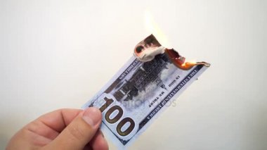 Yanan bir yüz dolarlık banknot tutan el