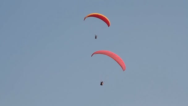 Parapente sobre as montanhas contra o céu azul claro — Vídeo de Stock