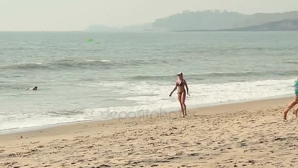 Красивая девушка играет Фрисби на пляже — стоковое видео