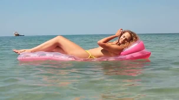 Beautiful young girl floating on a mattress in the sea — Stock Video