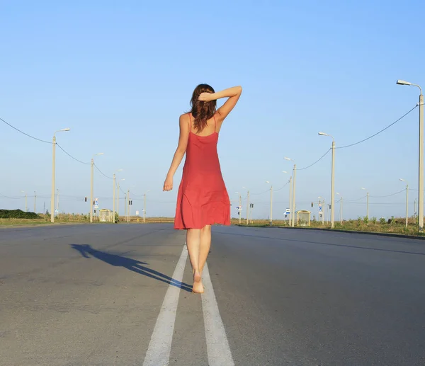 Beautiful female go away on empty road — Stock Photo, Image