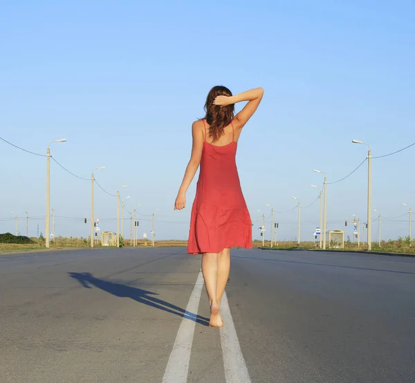 Beautiful female go away on empty road — Stock Photo, Image