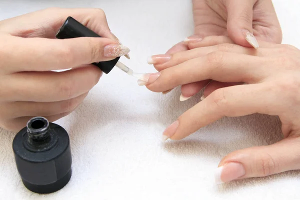 Manicure making - female hands, covering of transparent enamel — Stock Photo, Image