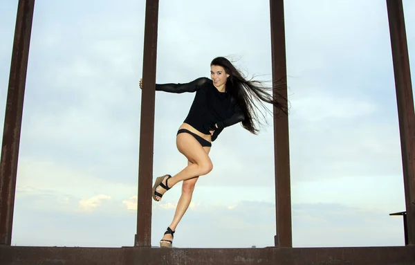 Chica joven posando en las estructuras oxidadas sobre el cielo azul — Foto de Stock