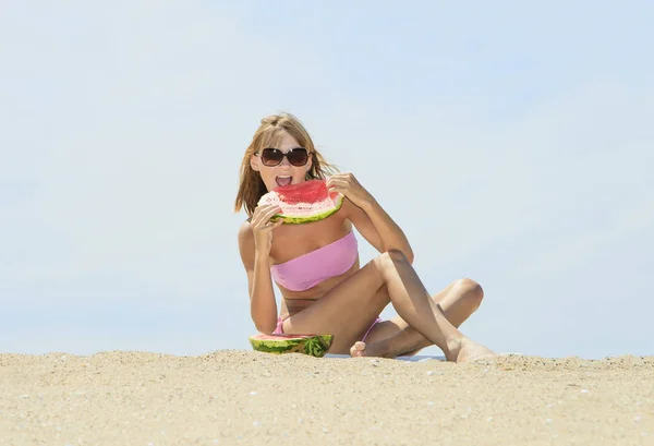 Mujer joven comiendo sandía en la playa — Foto de Stock