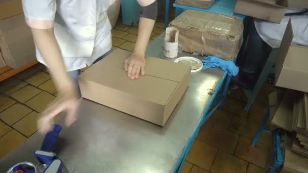 Woman hands holding packing machine and sealing cardboard boxes with adgesive tape — Stock Video