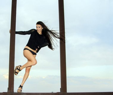 genç kız üzerinde mavi gökyüzü paslı yapıları üzerinde poz