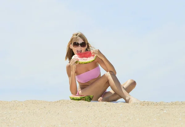 Mujer joven comiendo sandía en la playa — Foto de Stock
