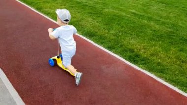 Çocuk raylar boyunca scooter sürüyor.