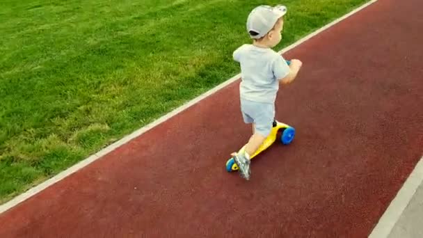 Der Junge Fährt Mit Dem Roller Die Gleise Entlang — Stockvideo