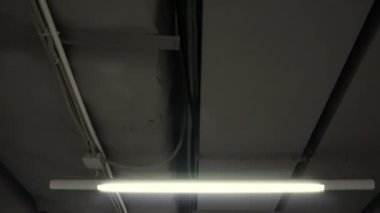 Tavanda floresan lambalar olan yeraltı koridorundaki sığınakta hareket var.
