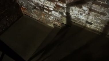 Metal bir merdivende tuğla duvarlarla bodruma inin.