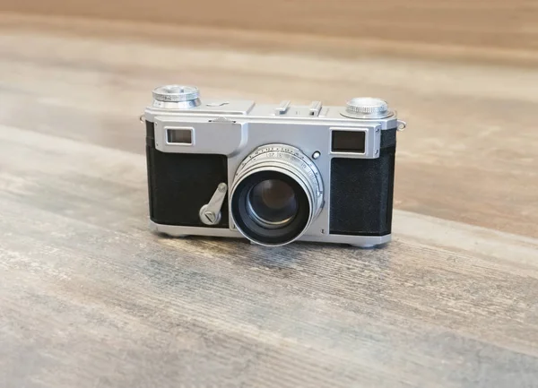 Old film photo camera on a wooden surface — ストック写真