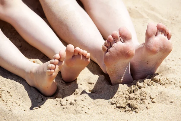 Fötter av mor och hennes barn i sanden — Stockfoto