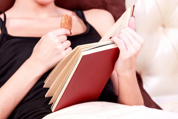 Kvinnan läser bok i en säng — Stockfoto