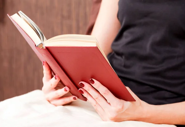 Крупным планом молодая женщина читает книгу в постели — стоковое фото