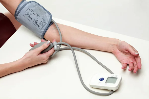 Женщина измеряет артериальное давление, изолированное на белом — стоковое фото