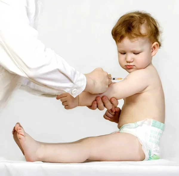 Médico administrándole a un niño una inyección de vacuna en el brazo — Foto de Stock