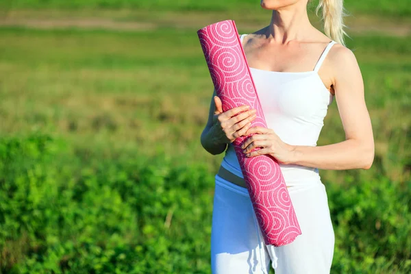 Yoga vrouw met een tapijt poseren buitenshuis — Stockfoto