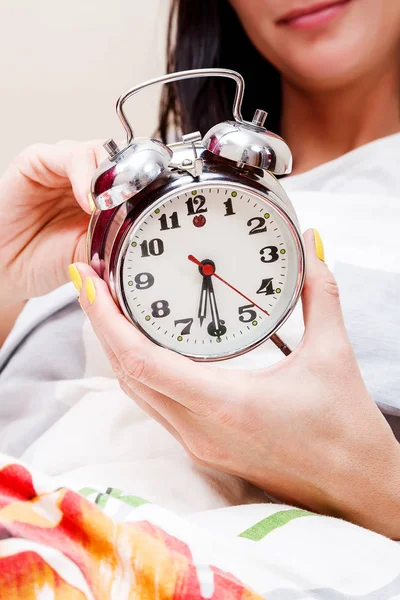 Mujer en una cama configurando el despertador — Foto de Stock