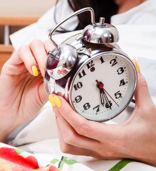 Mujer en una cama configurando el despertador — Foto de Stock