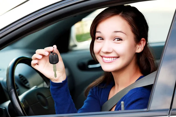 Mooie lachende gelukkig meisje toont de auto sleutel in haar hand — Stockfoto