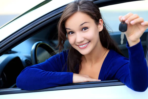 Красивая молодая улыбающаяся счастливая девушка показывает ключ от машины в руке — стоковое фото