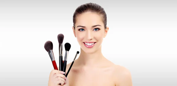 Красивая женщина с кисточками для макияжа на сером фоне с копирайтом — стоковое фото