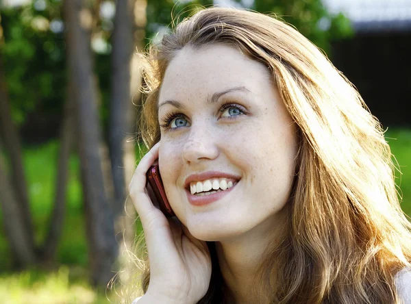 Strzał zbliżenie młoda kobieta uśmiechający się mówi przez telefon komórkowy — Zdjęcie stockowe