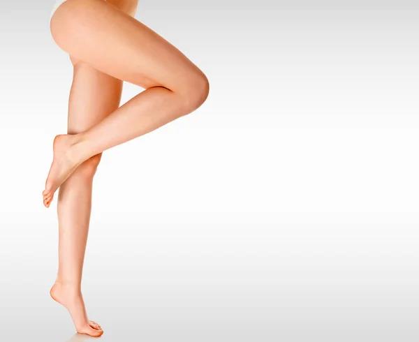Dlouhá ženské nohy na šedém pozadí s copyspace — Stock fotografie