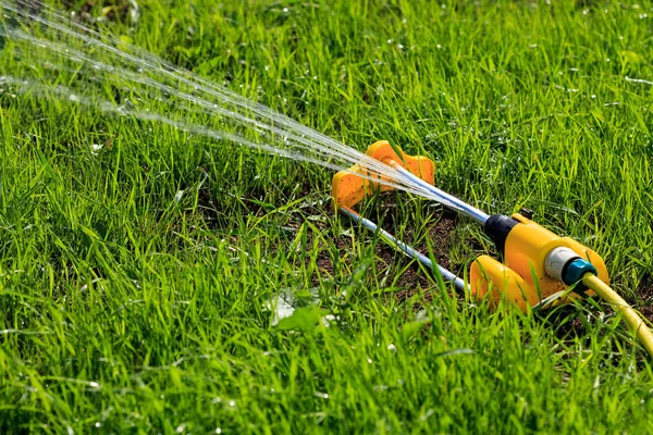 特写镜头的绿草域上喷涂水的草坪洒水器。灌溉系统 — 图库照片